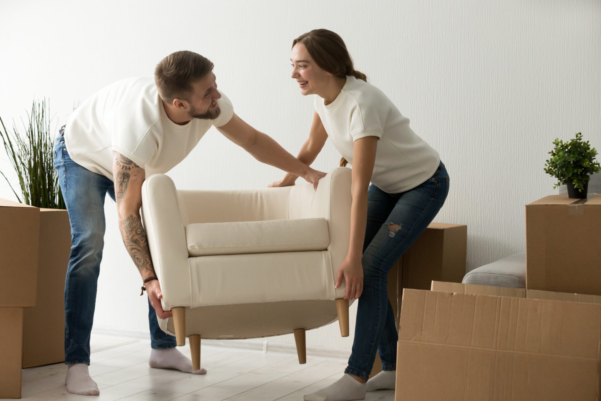 Young couple carrying chair together, house improvement, modern furniture in new home concept, men and women moving into own flat after relocation furnishing living room, remodeling and renovation